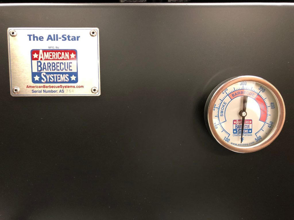 Temperature gauge on the outside, with the American Barbecue Systems logo. 
